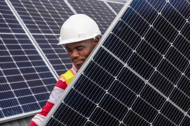 African man carrying a solar panel